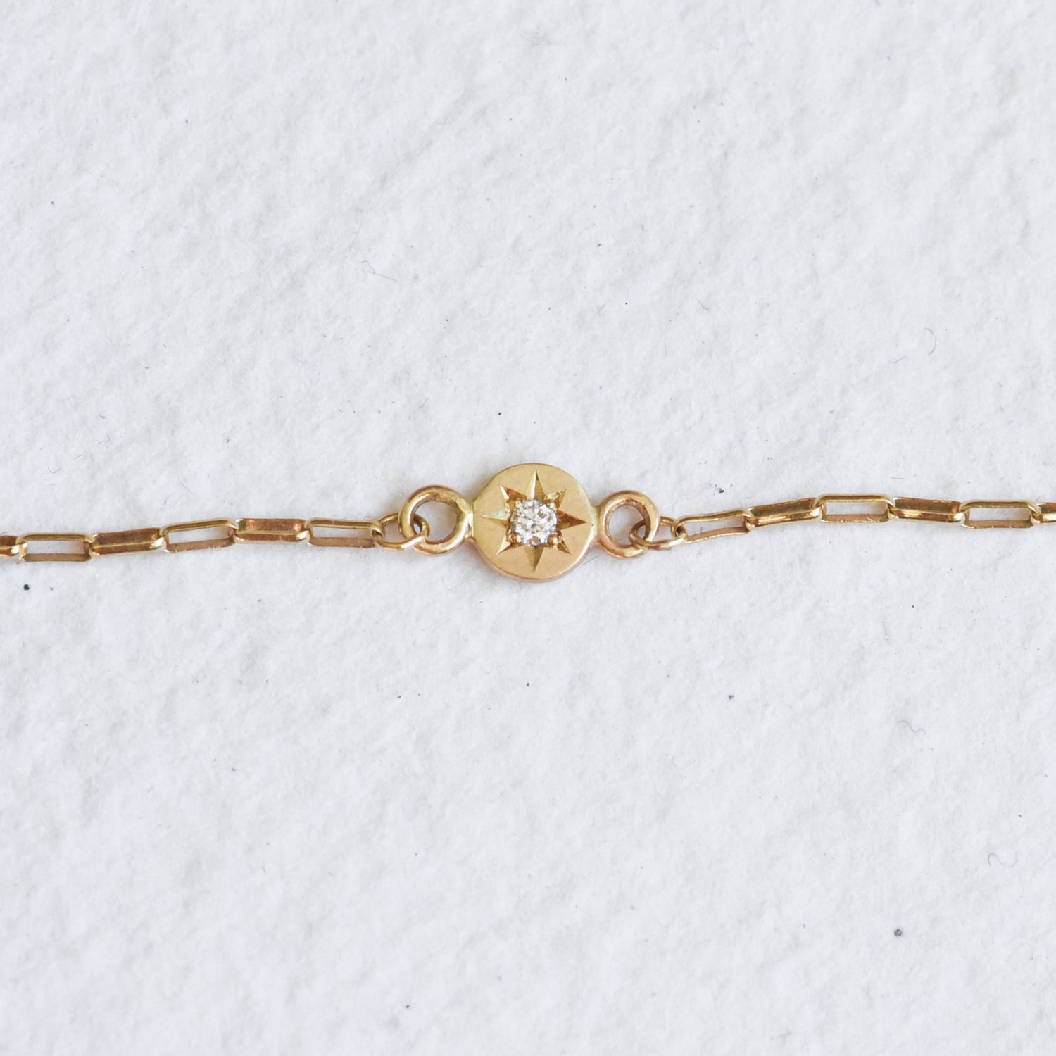 Detail shot of the diamond star setting on the gold chain bracelet, emphasizing the intricate hand engraving and fine craftsmanship of the gold setting.