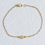 Close-up of the solid 14k yellow gold chain bracelet, showcasing hand-engraved details and a diamond set in a classic star setting on a delicate gold chain.