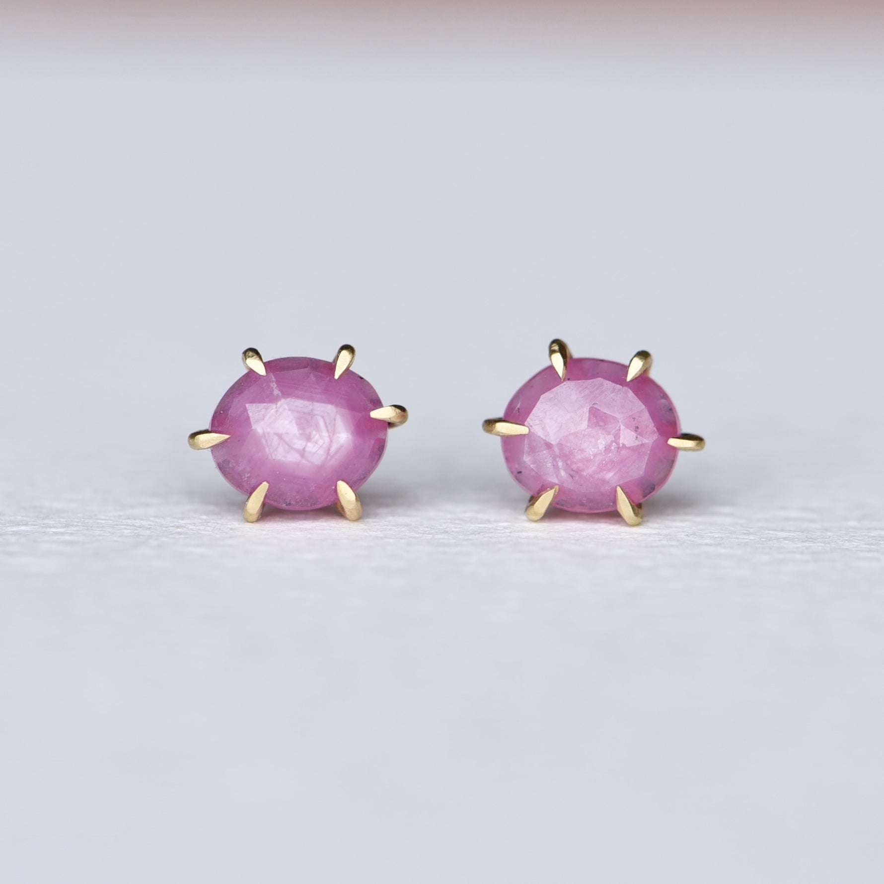 Close-up of Fierce Pink Sapphire Studs in 18k Gold, sparkling with vivid pink sapphires against a soft background.