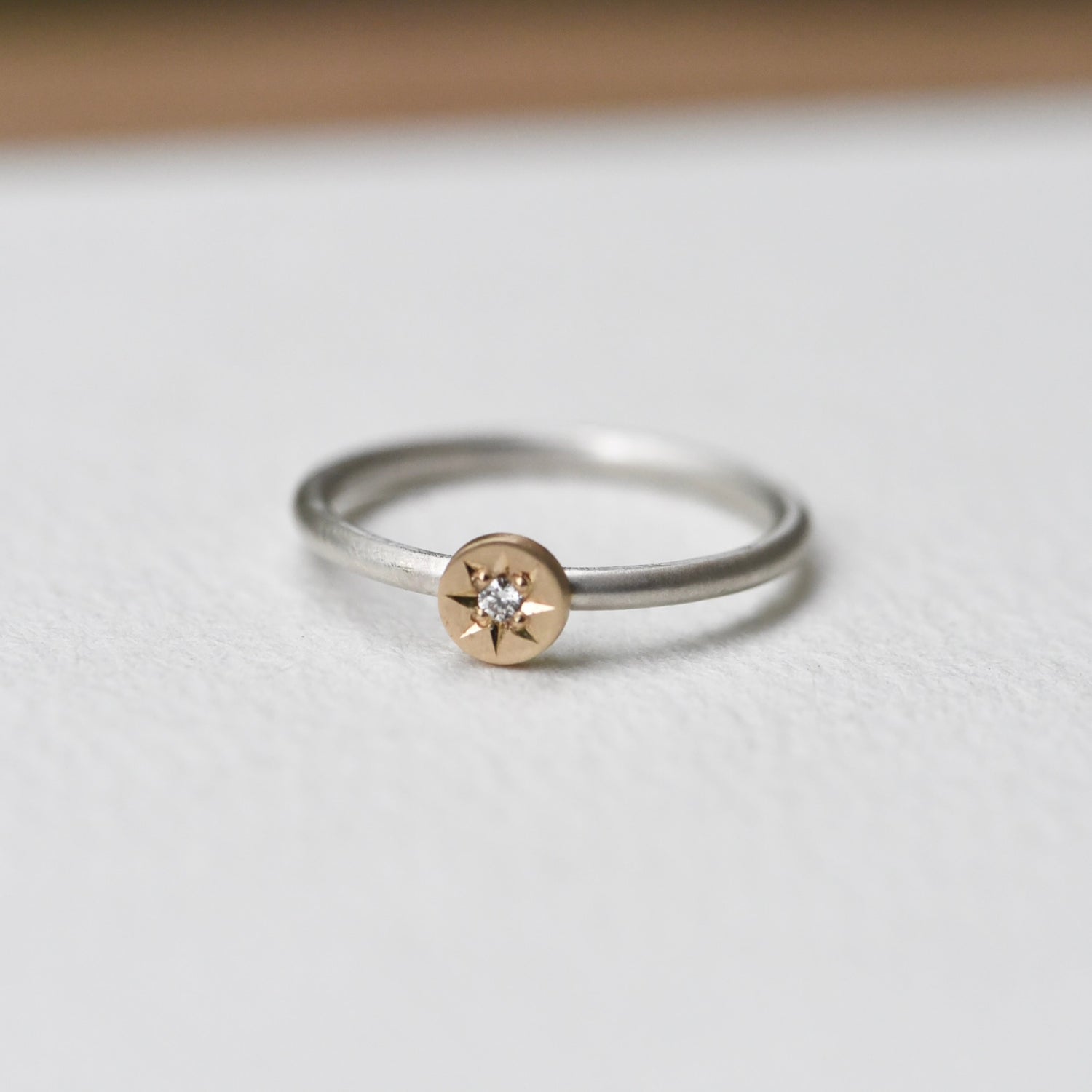 Continuum Silver + 14k yellow gold petite stacker ring with a hand-engraved star setting holding a small round diamond, shown on a white background.