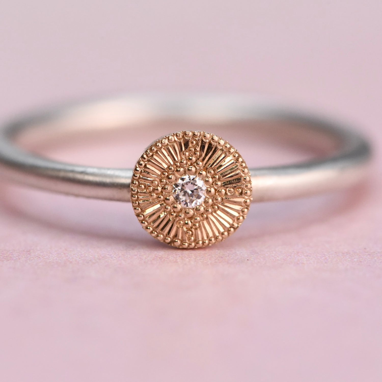 Gold ring with a diamond on a pink background