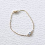 Close-up of the solid 14k yellow gold opal chain bracelet, showcasing a luminous opal set in a delicate gold bezel on a fine gold chain.