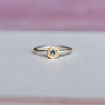 Front view of a handcrafted sterling silver ring with a 14k yellow gold bezel-set blue sapphire and hand-engraved starburst details by Corkie Bolton Jewelry.