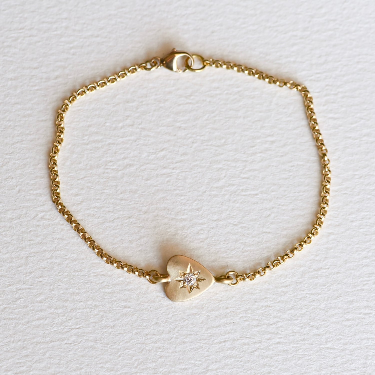 Overhead view of the bracelet laid flat, displaying the full length of the rolo chain and the centered heart charm.