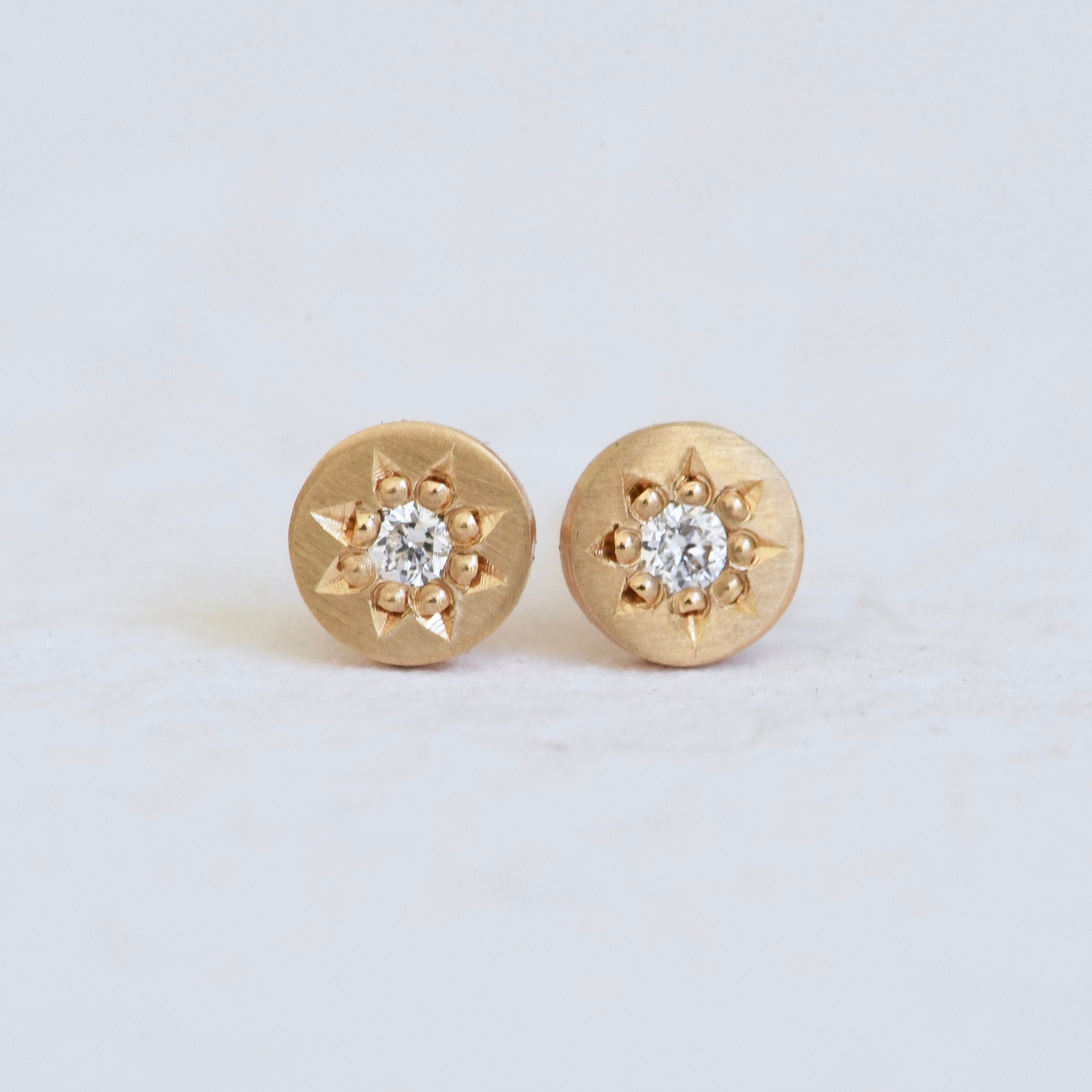 Gold hand engraved stud earring with round diamonds and star settings.