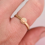 Artisan jeweler’s 10 K yellow gold ring size 7 featuring a smiley face design with responsibly sourced diamonds. Modeled on a hand.