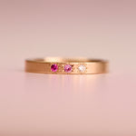 14k yellow gold ring featuring two pink sapphires and a misfit diamond in hand-engraved star settings, designed by Corkie Bolton Jewelry.