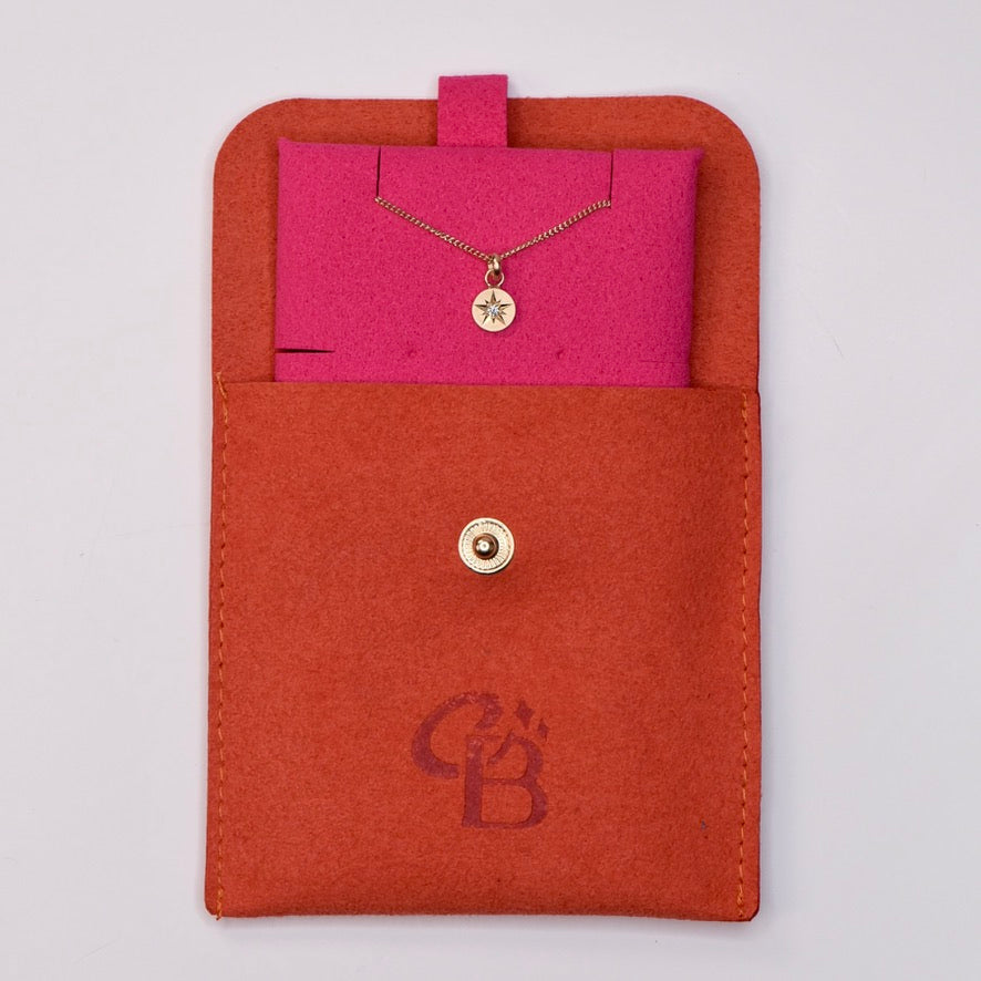4k gold star-set diamond charm necklace displayed in a pink insert inside a branded CBJ jewelry pouch.