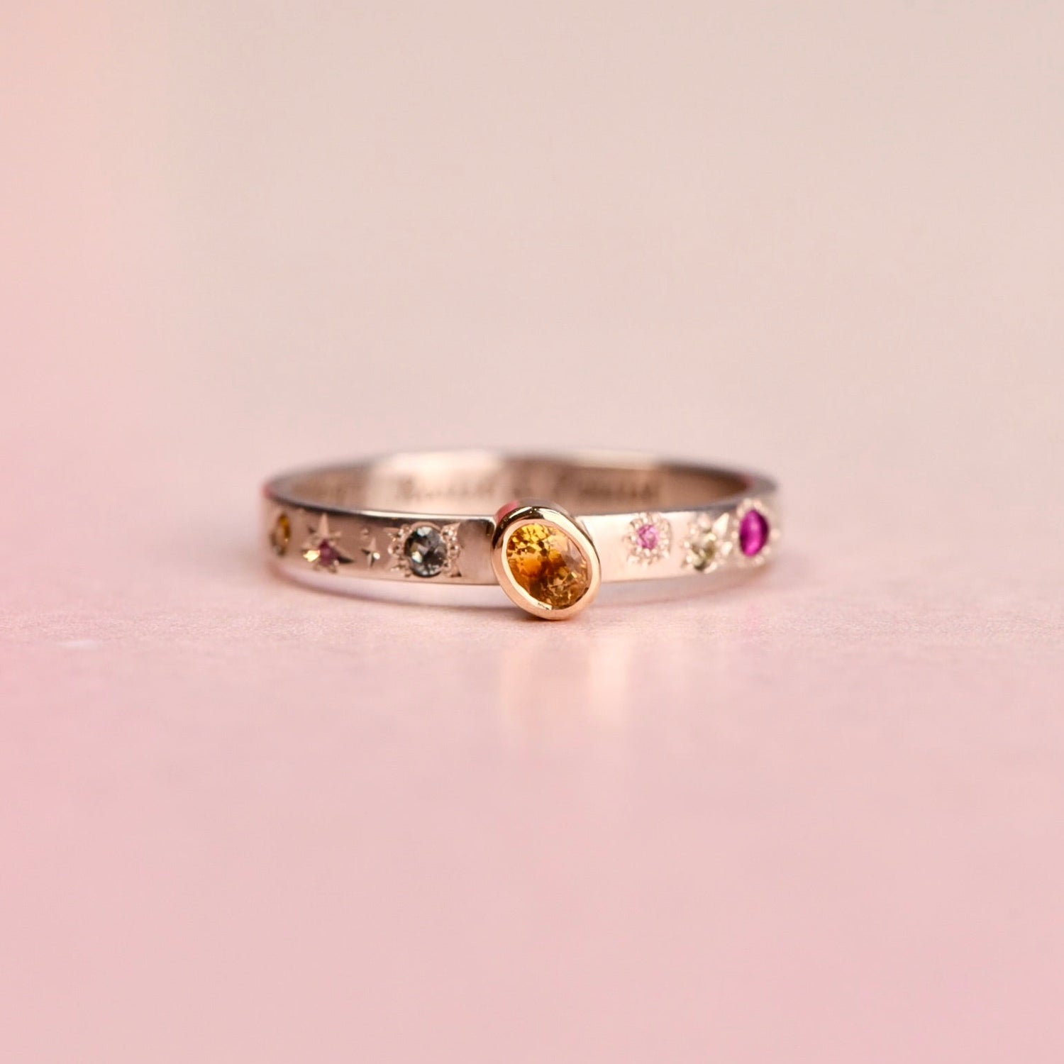 Ring with multicolored gemstones on a pink background