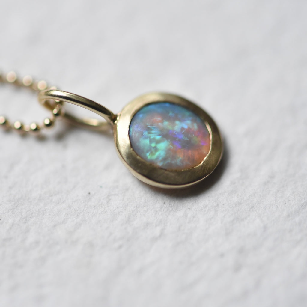 A gorgeous opal charm set in 14k yellow gold on a 14k yellow gold ball chain.