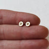 Petite, hand engraved 14k gold and diamond stud earrings by Corkie Bolton Jewelry held in a hand.