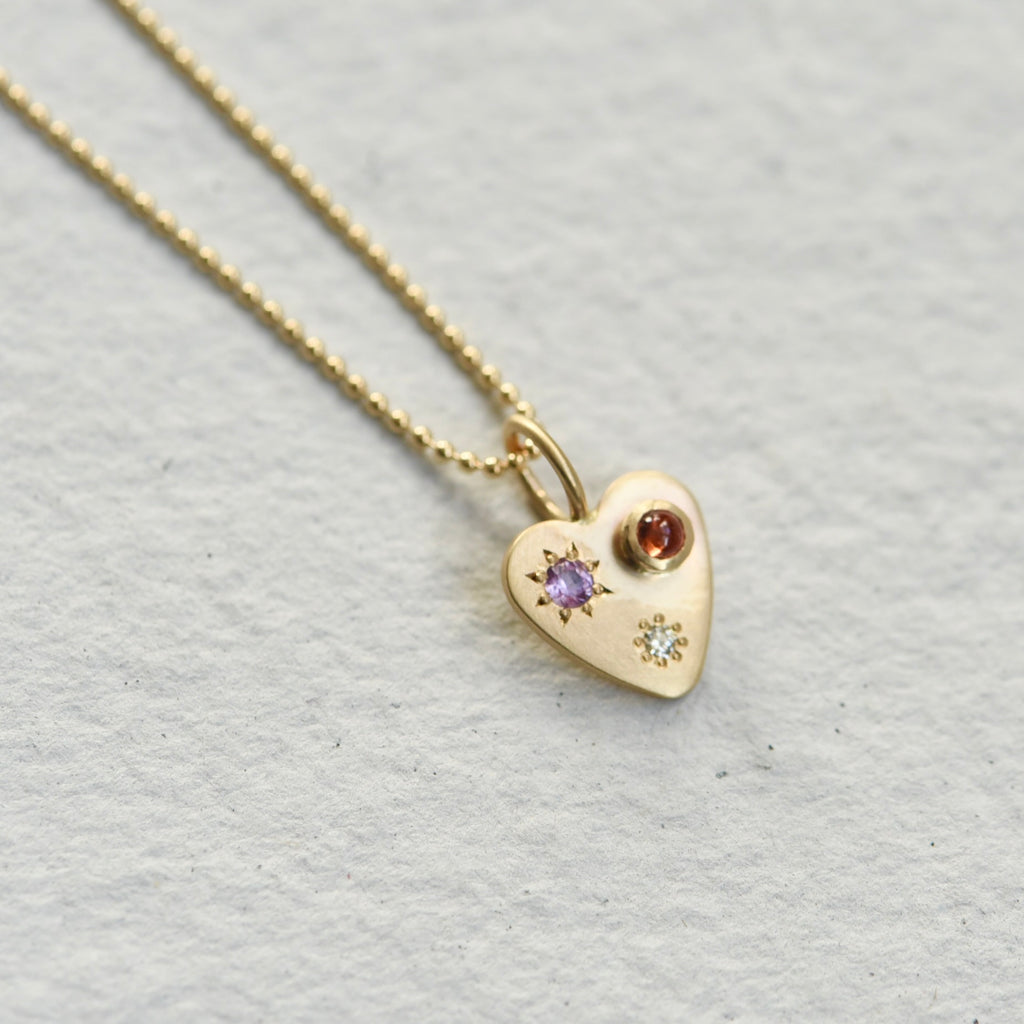 Gold heart charm, set with sapphires and a diamond. Hand engraved by Corkie Bolton.