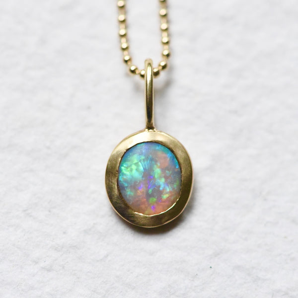 A gorgeous opal charm set in 14k yellow gold on a 14k yellow gold ball chain.