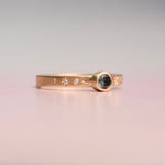 Gold ring with gemstone and star designs on a gradient background