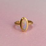Gold ring with an opal stone on a pink background