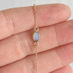 Close-up of the solid 14k yellow gold opal chain bracelet, showcasing a luminous opal set in a delicate gold bezel on a fine gold chain.