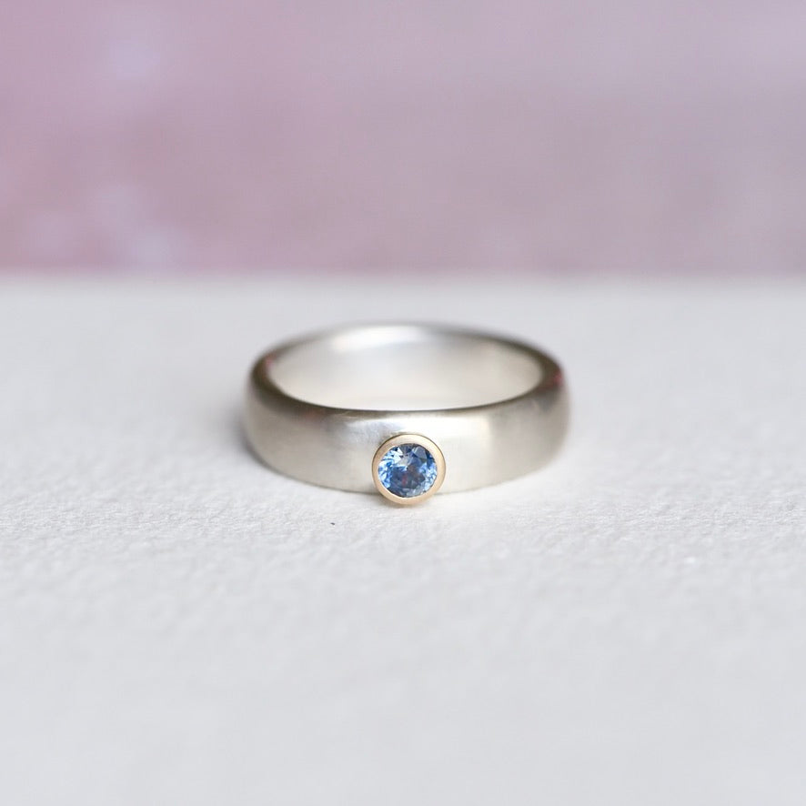 Montana sapphire ring front view – natural blue sapphire set in 14k yellow gold bezel on wide sterling silver band, handmade by Corkie Bolton.