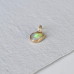 A teardrop flashy opal set in 14k gold as a charm, created by Corkie Bolton Jewelry.