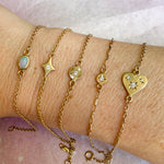 Gold bracelets with various charms on a wrist against a white background