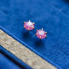 Pink sapphire stud earrings in 18k yellow gold by Corkie Bolton Jewelry in a jewelry display.