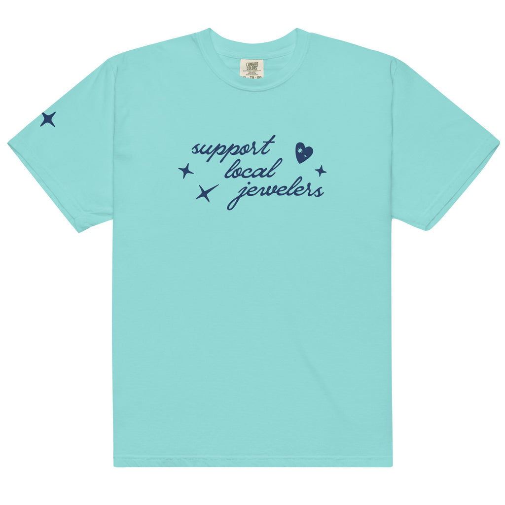 Lagoon Blue, turquoise, short-sleeve T-shirt with a navy blue design on the front. The design includes the phrase "support local jewelers" in cursive font, accompanied by small star-like shapes and a heart with a sparkle inside. A small star detail is featured on the left sleeve.