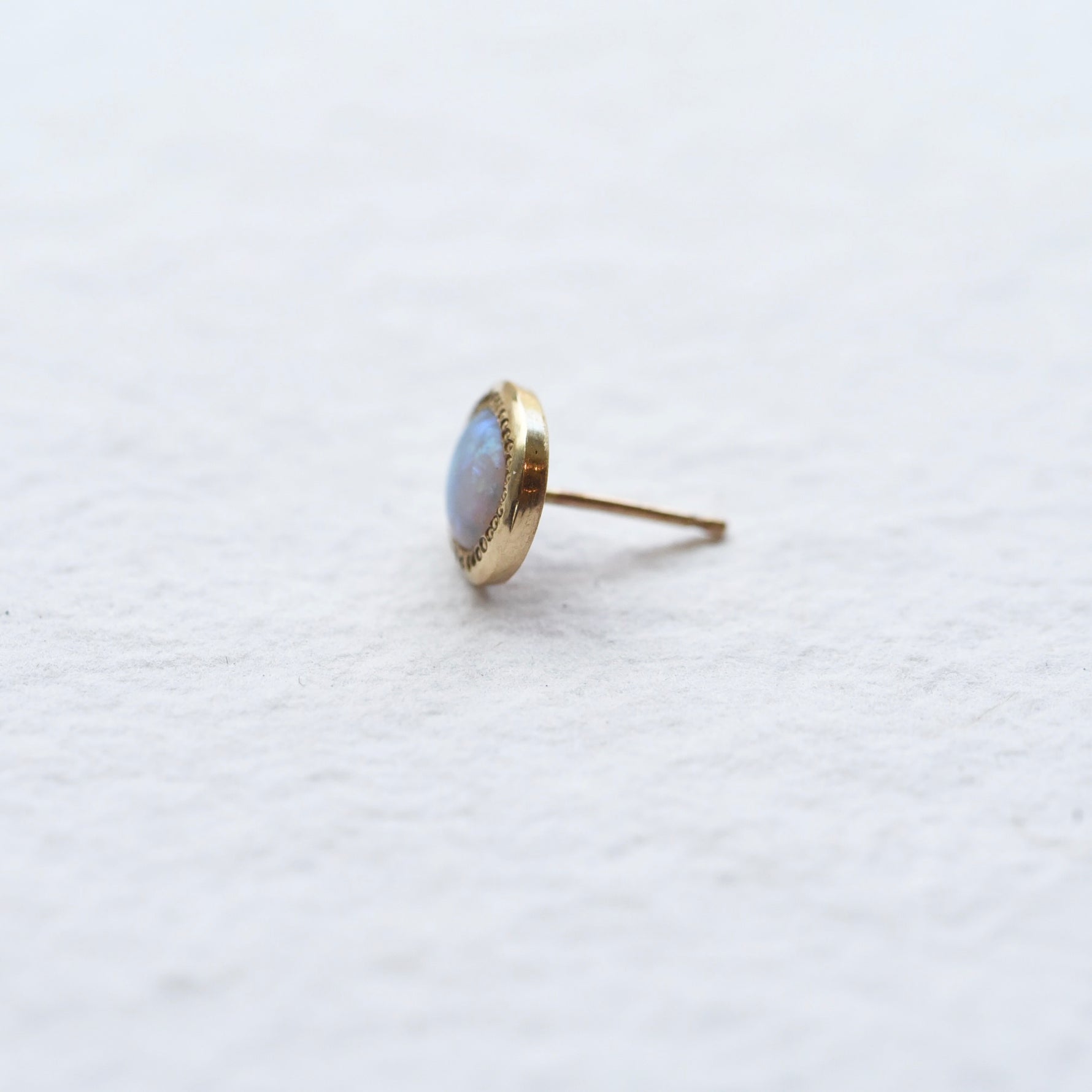 Side view of the matte opal gold stud earring, highlighting the delicate craftsmanship of the gold setting and the subtle iridescence of the opal