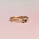 Gold Sapphire ring with 'One Day At A Time' laser engraved inside the ring on a pink background