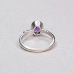 Back view of a sterling silver bezel-set oval amethyst ring showing the band and setting construction