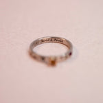Silver ring with 'Resist & Persist' engraving on a beige background