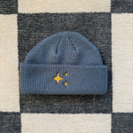 Petrol Blue Sparkle Fisherman Beanie - a neutral blue beanie featuring a gold embroidered sparkle, blending warmth and a sophisticated shimmer for a standout accessory.