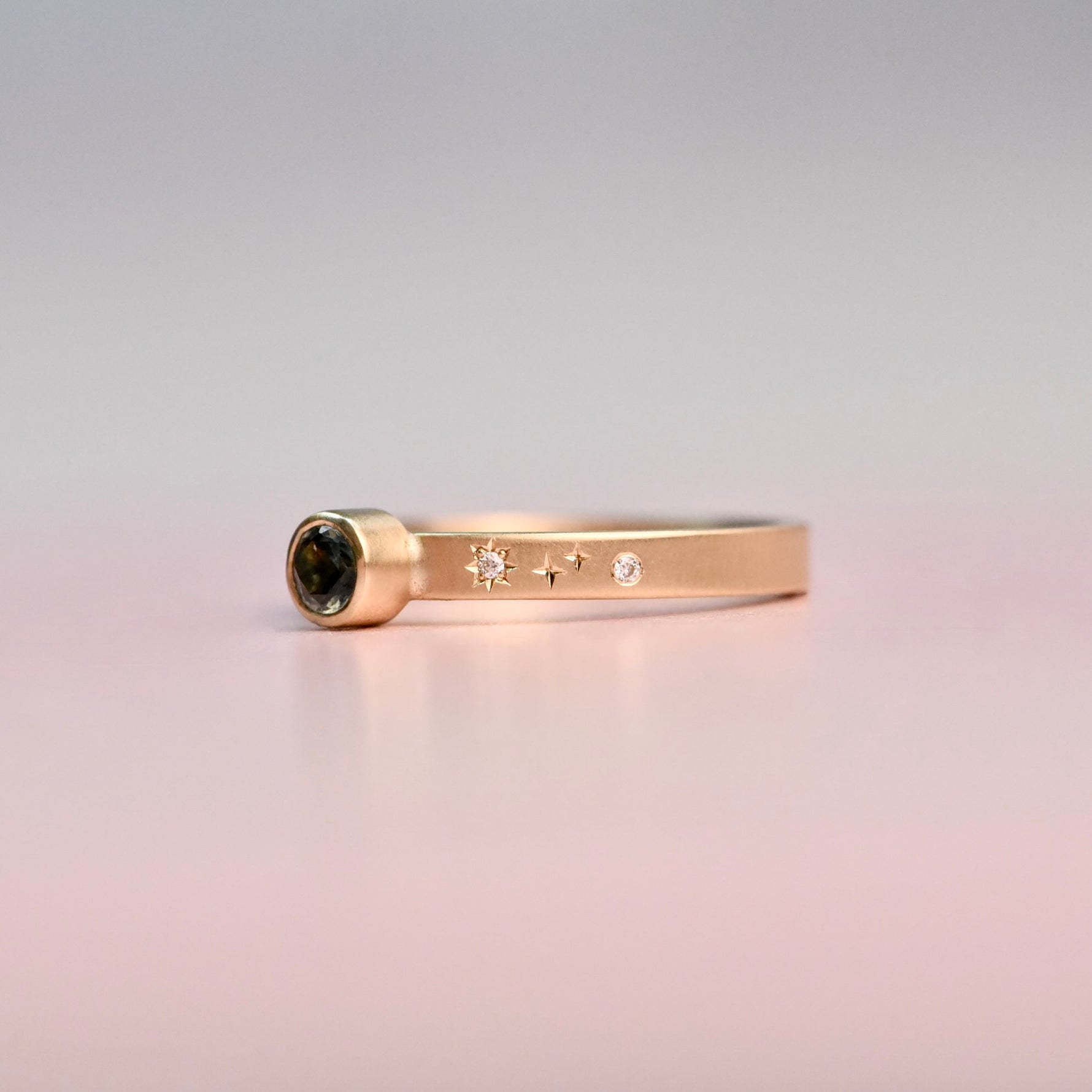 Gold ring with hand engraved cosmic diamonds on a gradient background