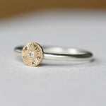 Gold and silver ring with a diamond on a light gray background