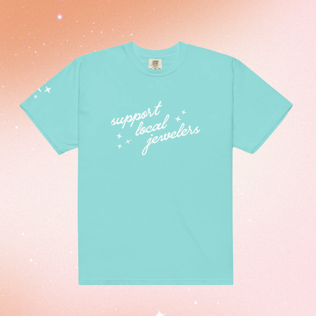 Light teal t-shirt with 'support local jewelers' text printed in white on the chest along with sparkle graphics.