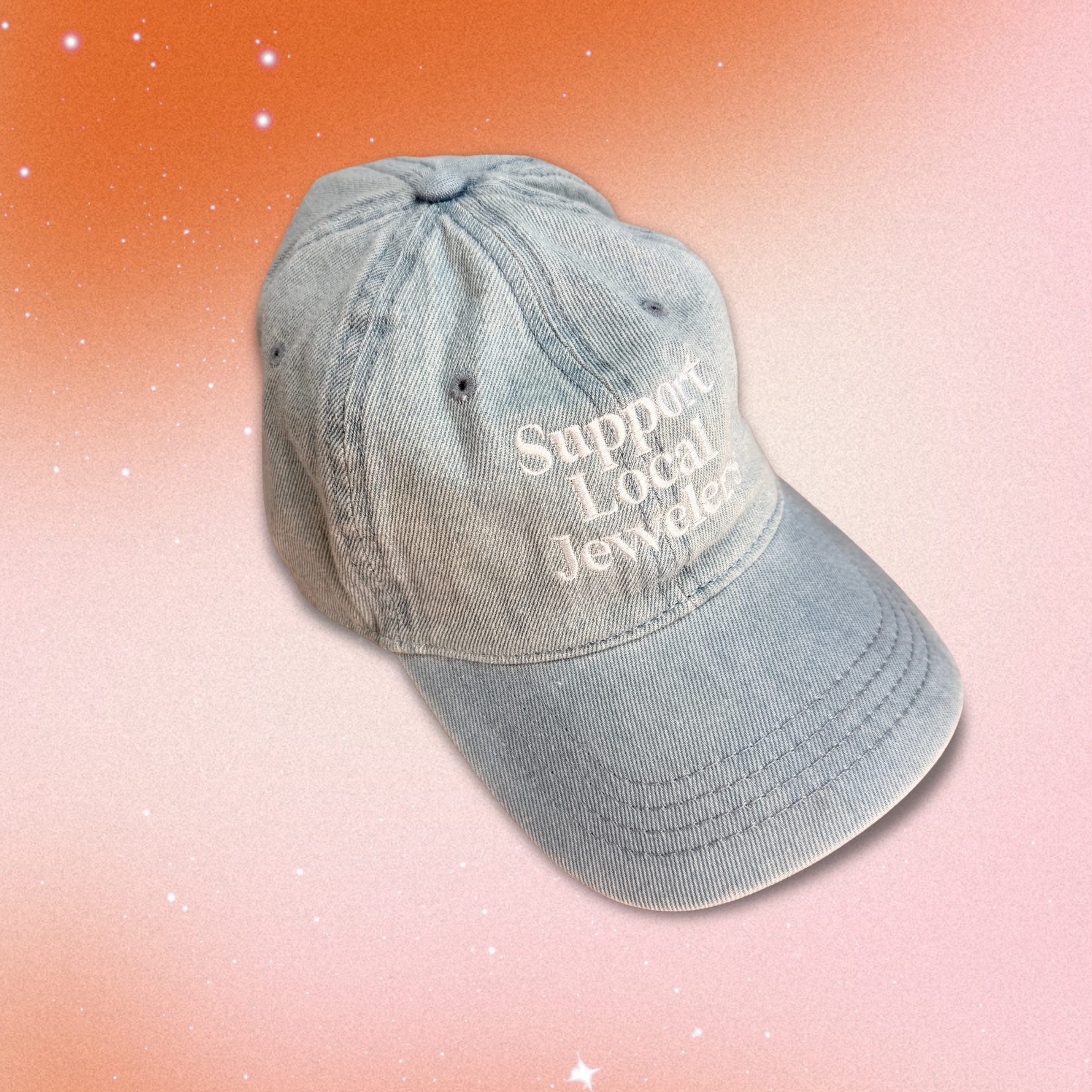 Light denim Support Local Jewelers hat with white embroidery, featuring a classic 6-panel design, adjustable strap, and soft 100% cotton construction. A relaxed, everyday cap that celebrates independent artisan jewelers.