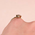 Side view of a gold ring worn on a finger, showing the teal diamond in a hand engraved star setting on the bezel