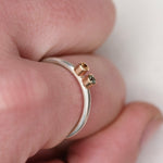 Close-up of a sterling silver stacker ring held in hand, showing two tiny sapphires in 14k gold bezels from the side