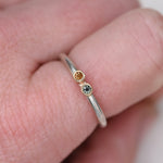 Slim sterling silver stacker ring with orange and blue sapphires in 14k gold bezels worn on a finger