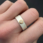 (IMAGE 2) The Waves Engraved 14k Silver Diamond Ring in size 8.5 worn on a hand, showcasing its textured wave-like band, 14k gold star setting, and sparkling diamond against natural skin tone.