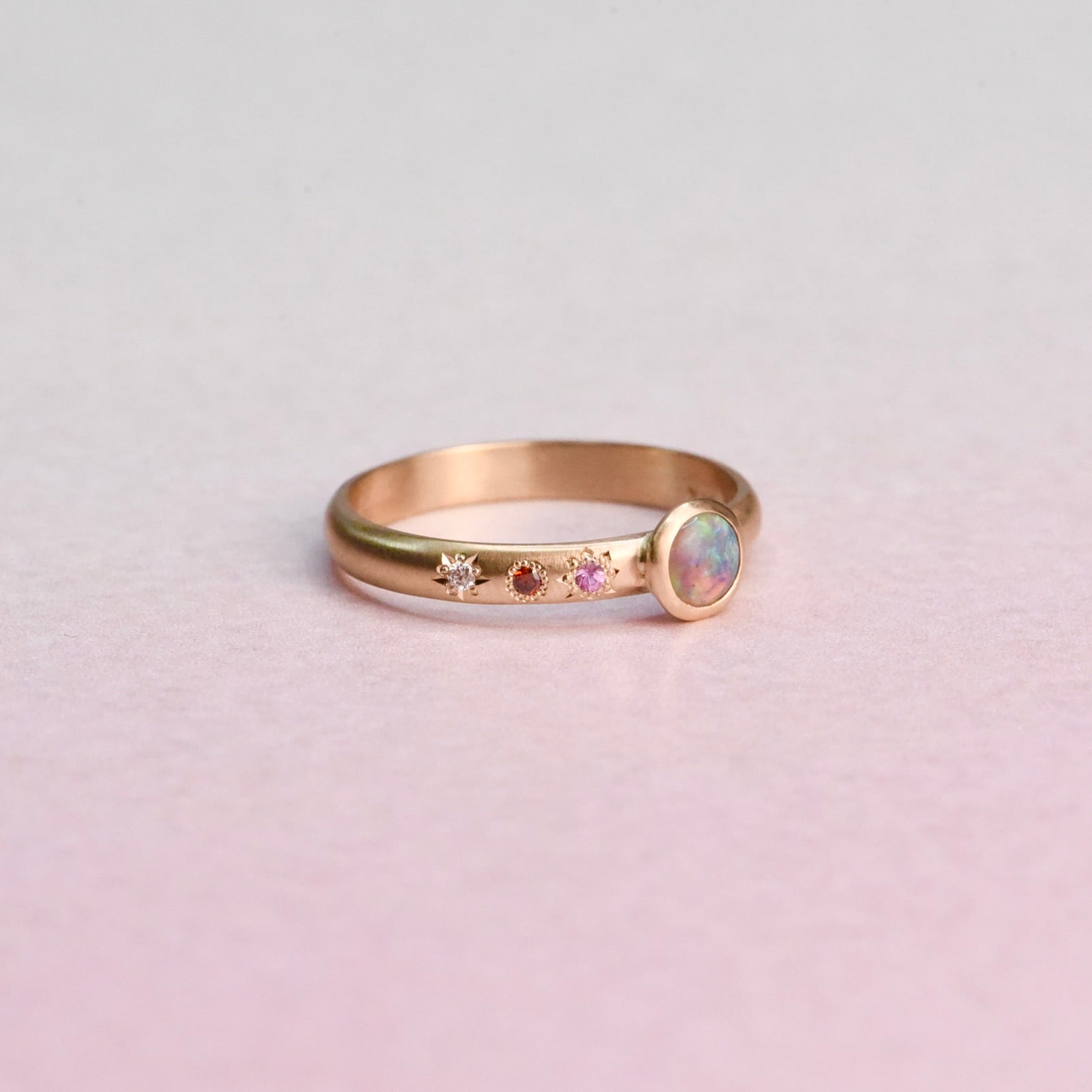 Flat lay of the Asymmetrical Black Opal + Sapphire 14k Gold Ring by Corkie Bolton Jewelry, featuring recycled gold, responsibly sourced gemstones, and delicate star engraving.