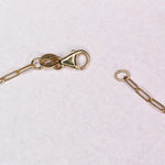 Gold chain with clasp on a light pink background