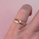 Vintage Confetti Diamond + Sapphire Band worn on a pinky finger, showing the multicolor stones and star-engraved details in soft natural light.