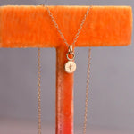 Gold necklace with a star pendant on an orange stand against a gray background