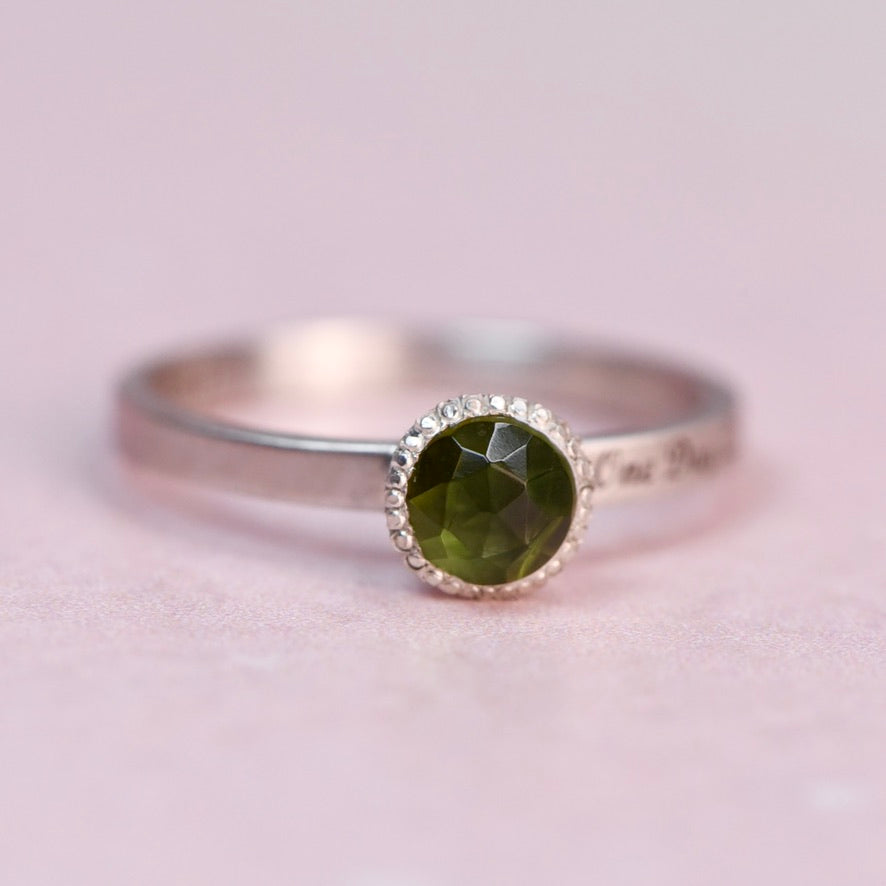 Side view of a Continuum silver band engraved with “One Day At A Time,” paired with a green rosecut tourmaline bezel setting.