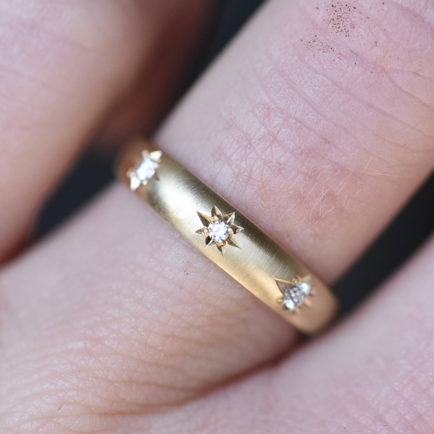 Gold ring with diamond accents on a finger