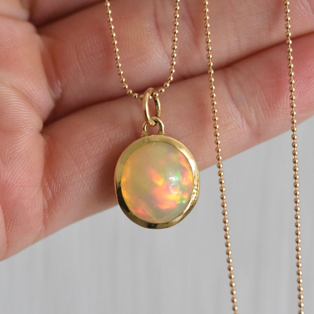 18k yellow gold charm featuring a gorgeous Ethiopian Opal that is responsibly sourced. Created by Corkie Bolton Jewelry.