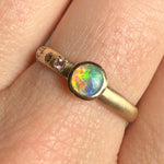 Close-up of the Lightning Ridge black opal cut by Ancients17, showing vivid flashes of green, blue, and neon orange in a smooth bezel setting on a handcrafted 14k yellow gold band.
