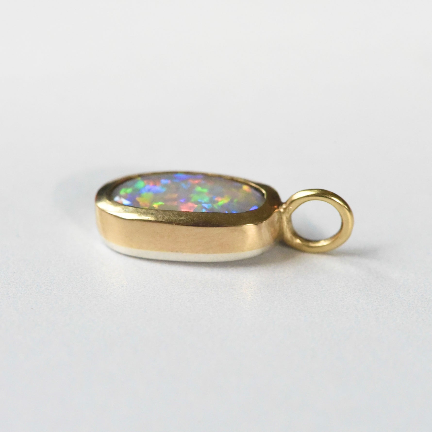 Handmade 22k yellow gold bezel set Lightning Ridge crystal opal pendant, fine silver back, by Corkie Bolton Jewelry Rhode Island on a white background
