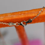 Close-up of a gold chain with clasp on an orange surface