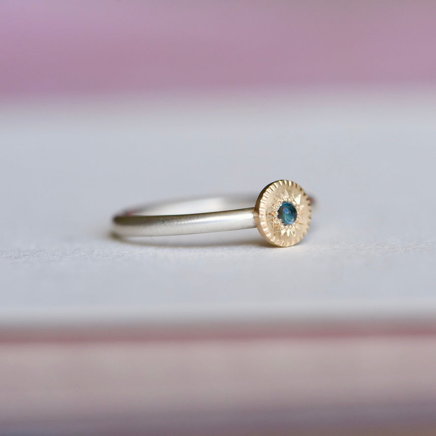 Side view of the Engraved Starburst Ring showing the mixed-metal design with sterling silver band, 14k gold star setting, and engraved details surrounding the blue sapphire.