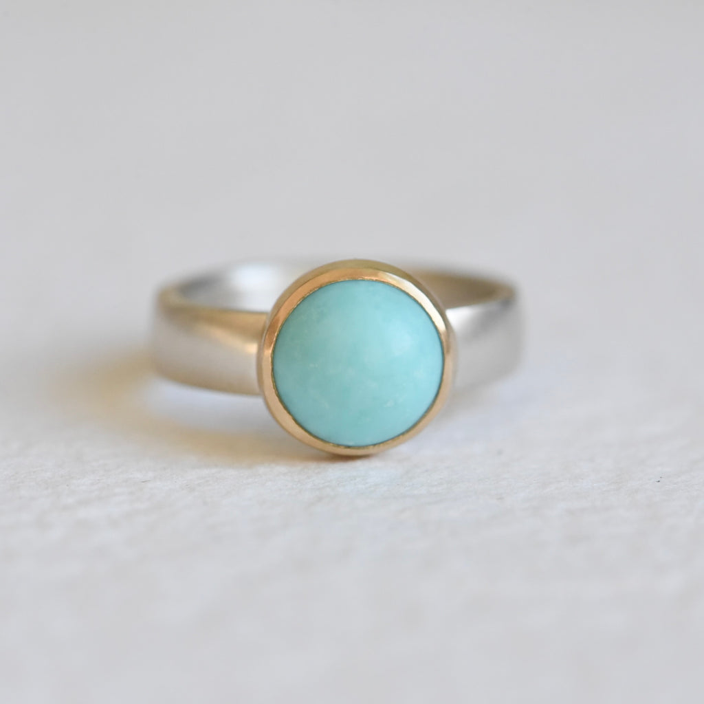 Outstanding Turquoise Mixed Ring on a white background, featuring a vibrant turquoise stone set in a 14k gold bezel with a textured silver band.